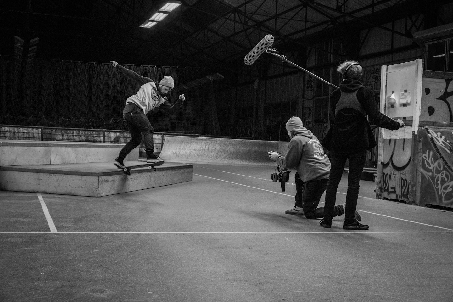Skateboarder doing a trick while a film crew records.